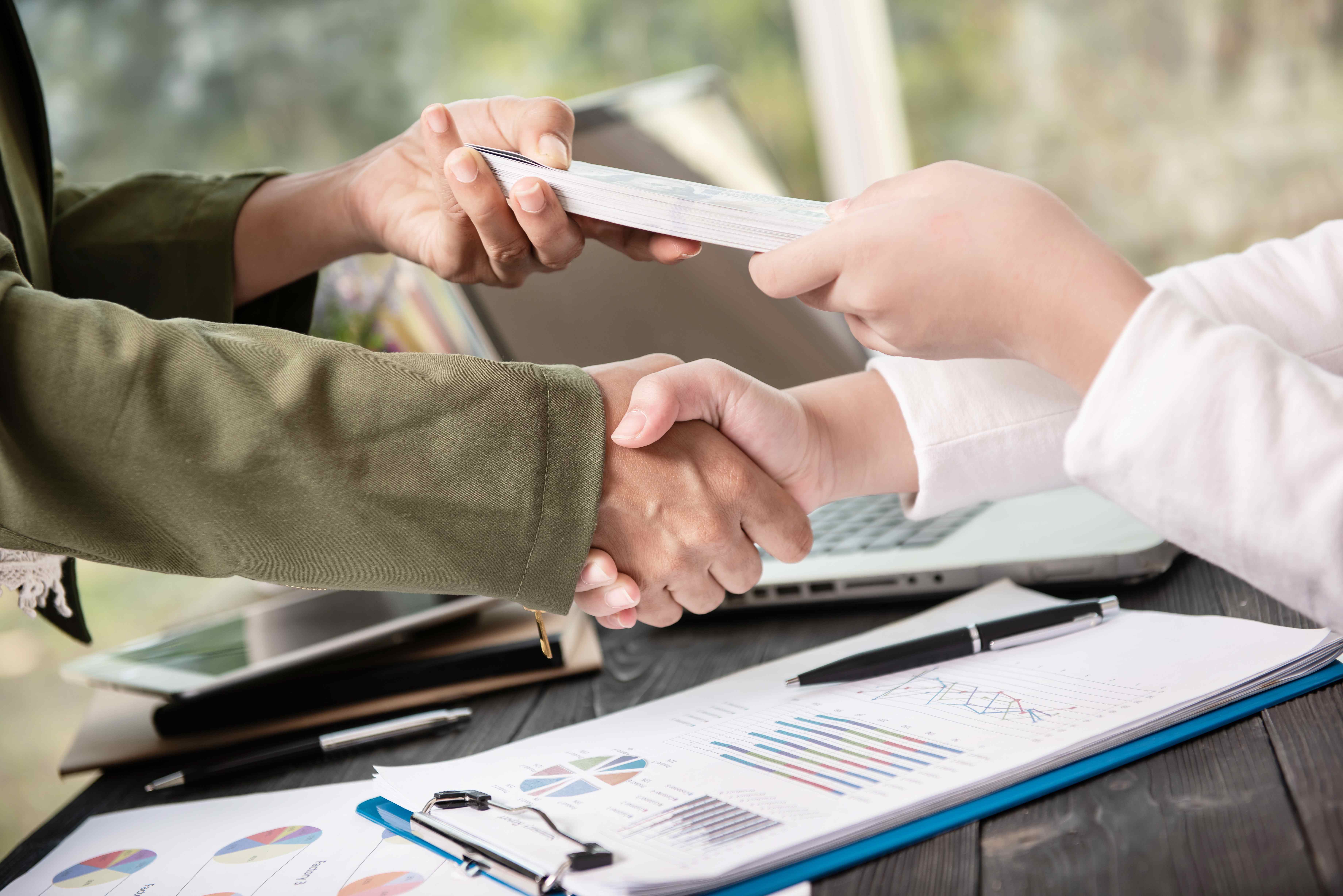 Two people shaking hands over financial documents, symbolizing debt consolidation
